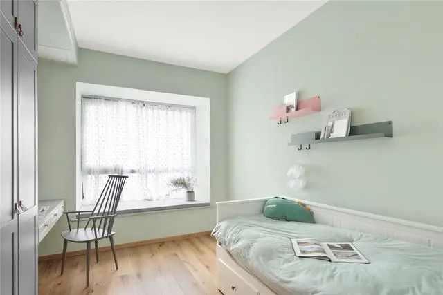 5儿童房墙壁大胆采用抹茶绿色，搭配浅色的实木地板装饰，使得次卧显得十分清新，有一种回归大自然的感觉，能够为孩子提供一种轻松惬意的生活环境。白色的小床非常精致，靠墙摆放，既能满足孩子休息，同时也不影响卧室的空间。书桌采用壁挂的安装方式，搭配一把舒适的椅子，日常办公学习更加轻松。.jpg